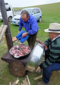 An uncle adding water to the cooking goat dish.