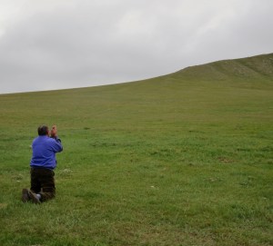 Honoring the spirits, a man kneels and bows in the direction of the shrine we visited earlier atop the hill.