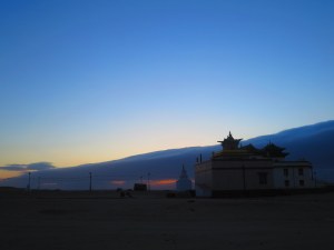 A restored monastery in the foreground, with a Buddhist shrine, a stupa, nearby.